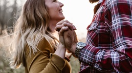 A photo of a man and woman happily looking at each other while holding hands